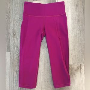Hot pink lululemon capri leggings with scalloped detail and back zipper pocket.